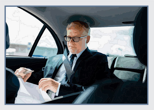 Businessman sitting in the back seat of a car reviewing documents.